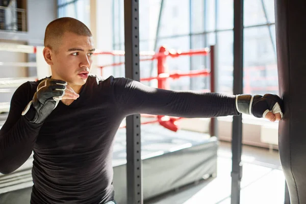 ファイトクラブ 訓練の速度および強さのボクシング練習中にサンドバックを打つ若い筋肉スポーツ男性の側ビュー肖像画 — ストック写真