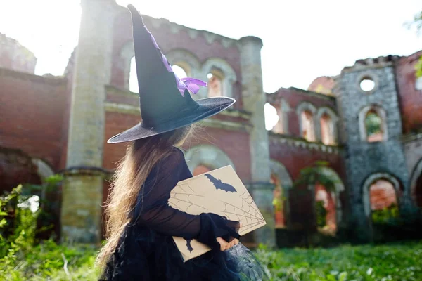 小巫婆与咒语书走向她的城堡在废弃的地方 — 图库照片