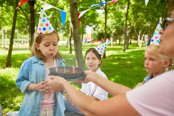希望したらケーキの誕生日キャップ吹きろうそくの女の子 — ストック写真