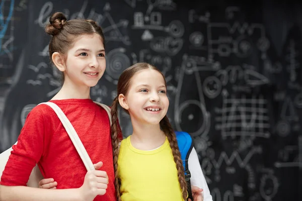 Omarmen Schoolmeisjes Permanent Tegen Blackboard — Stockfoto