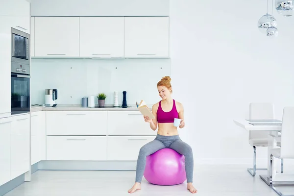 Портрет Улыбающейся Рыжеволосой Женщины Выполняющей Упражнения Дома Сидящей Мяче Читающей — стоковое фото