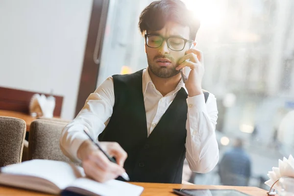 Young man organizing work and speaking to co-worker by the phone