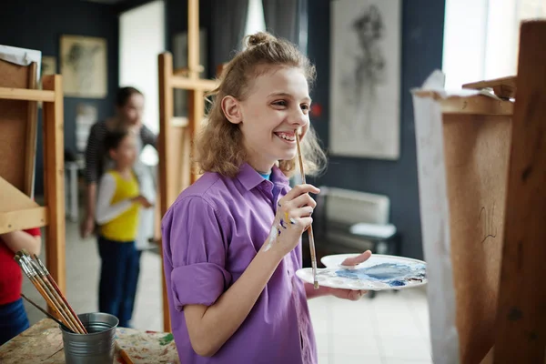 水彩絵の具と絵筆が彼の絵を見て幸せな少年 — ストック写真
