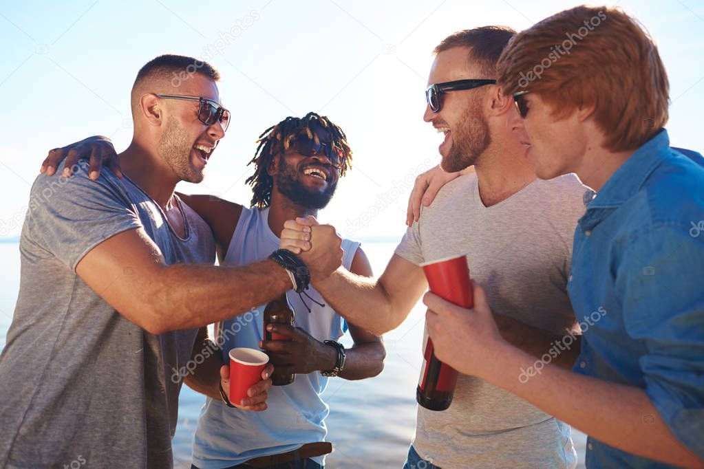 Friendly guys having fun on summer weekend by seaside