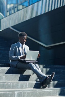 Ciddi satıcı ya da açık havada merdiven üzerinde otururken mali verilere bakarak latop ile tüccar