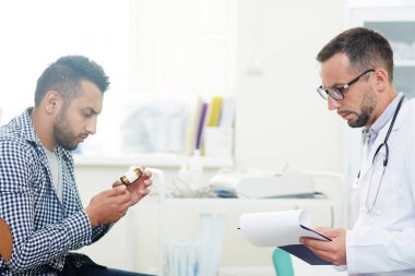 Genç hastanın doktoru ile önünde uyuşturucu hapı şişesiyle bakarak