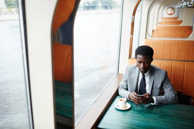 Kahve tarafından kafede otururken smartphone içinde zarif adam manifatura