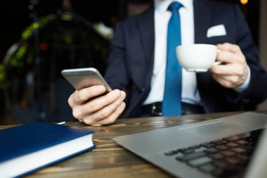 Çalışma kafe, holding cep telefonu, manifatura ve kahve bardağı içme tanınmaz zarif işadamı closeup düşük açılı