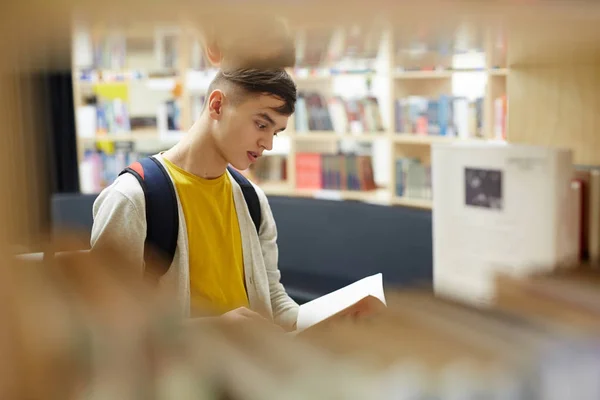 好奇的家伙读大学图书馆的书 — 图库照片