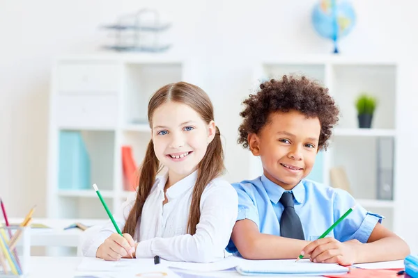 Multiraciale Schoolkinderen Met Potloden Zitten Door Bureau Dicht Bij Elkaar — Stockfoto