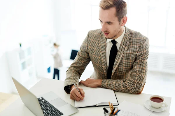 Giovane Impegnato Scrivere Nel Suo Taccuino Leggere Dati Online Laptop — Foto Stock