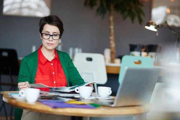 Mujer Joven Seria Mirando Través Revista Diseño Cafetería — Foto de Stock