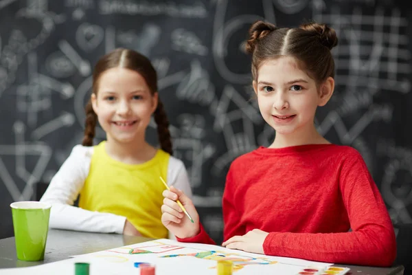 Birlikte sanat stüdyo sınıfta boyama sırasında kameraya bakarak mutlu iki kızın portresi