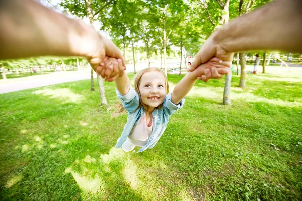 小孩子被她的父母在公园绿草旋转 — 图库照片