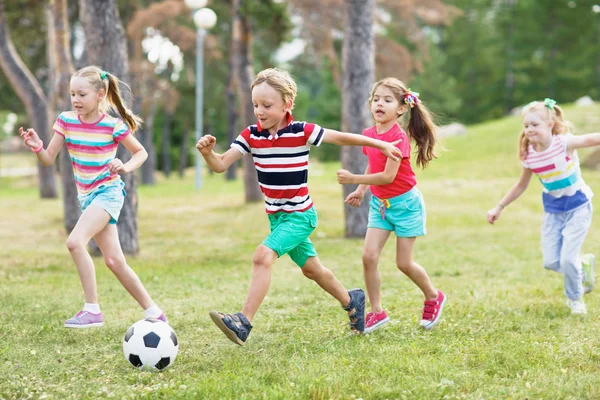 小学生在夏天穿在公园的绿色草坪上踢足球 — 图库照片