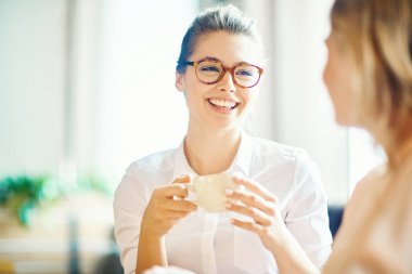 Çekici genç kadın rahat küçük kafede en iyi arkadaşı dışarı asılı iken hoş kokulu kahve zevk çekici gülümseme ile baş ve omuzlar portresi