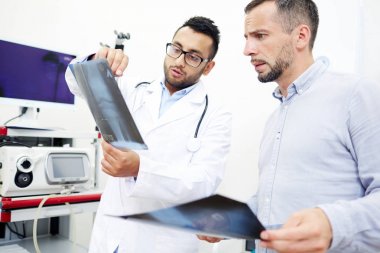 X-Ray görüntü erkek hastaya gösterilen ve onu sırasında randevu modern ofisindeki gerekli tedavi reçete yakışıklı sakallı doktor