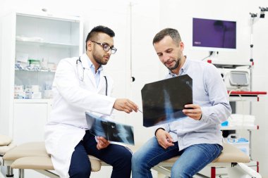Genç adam bir röntgen sonuçlarını doktoru tarafından gösterilen arıyorum