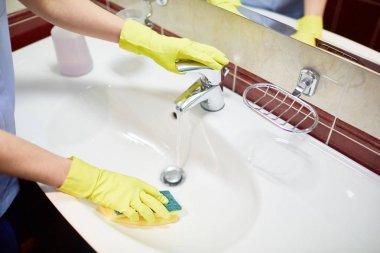 Lavabo temizlik sırasında otel-hizmetçi eldivenli elleri