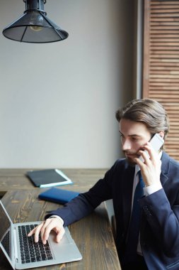 Laptop ile çalışma ve smartphone vasıl ahşap masa tarafından konuşma genç başarılı işadamı portresi