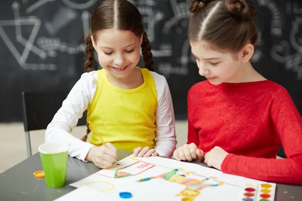 两个微笑的小女孩的肖像画在艺术工作室班坐在黑板上 — 图库照片