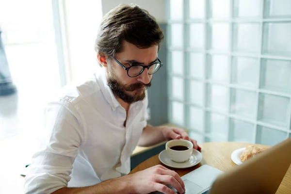 ネットで閲覧または欠員のため カフェで朝食を求めて若い男 — ストック写真