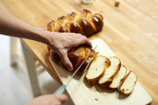 人用刀子切开了新鲜地被烘烤的面包在木板材 — 图库照片
