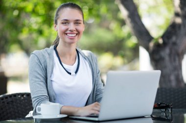 Çekici genç iş kadını rahat açık kahvehane içinde laptop üzerinde çalışırken dişlek gülümseme ile kameraya bakarak portresi