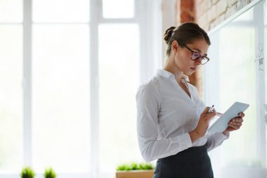 Beyaz tahta tarafından ayakta ve ders için hazırlanıyor tablet ile genç öğretmen