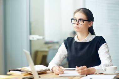 Düşündüğünü veya çalışma günü sonu için bekleyen ciddi ofis çalışanı