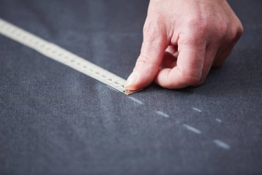 Yetenekli terzi Atölyesi çalışma closeup: eller işaretleme ve kumaş giyim yaparken ölçme