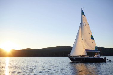 Lüks yatta gün batımında yüzen iki insan