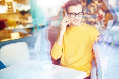 Buket çiçek Tarih için beklerken kafede telefonla konuşan gülümseyen genç adam portresi