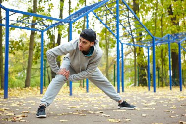 Tam uzunlukta portre yakışıklı sporcu eğitim sokak egzersiz Park önce kasları Isınma
