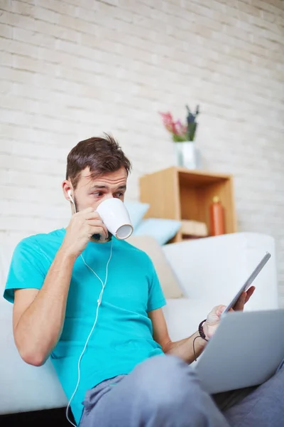 Brown Haired Young Man Reading Article Tablet Listening Music Drinking — Stock Photo, Image