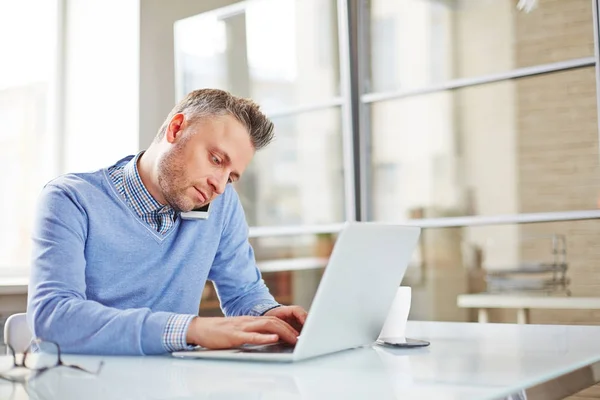 Serious Middle Aged Businessman Typing Laptop While Calling Colleague Phone — Stock Photo, Image