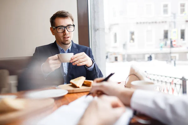 ビジネス パートナーと話をお茶のカップを持つ若い従業員 — ストック写真