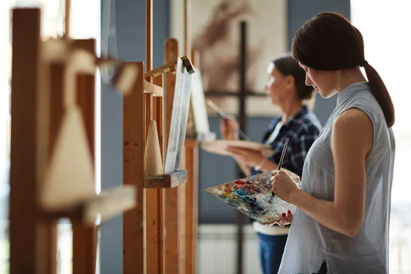 オイル キャンバスに絵を描いて美術の授業で若い女子学生像側ビュー — ストック写真