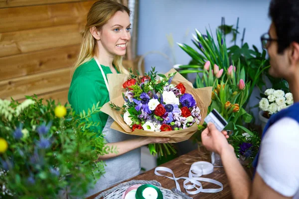 Floristería Sonriente Con Flores Mirando Joven Comprador — Foto de Stock