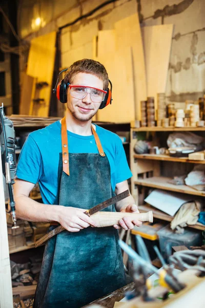 木造の詳細を保持しているカメラを見て 若い男を笑みを浮かべて Carpenting スタジオでの作業の肖像画 — ストック写真