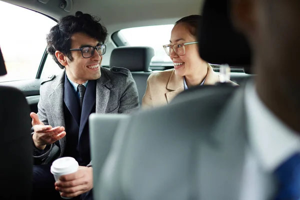 两个成功的商人骑在出租车后座的肖像 乐呵呵地微笑和谈话的方式工作 — 图库照片