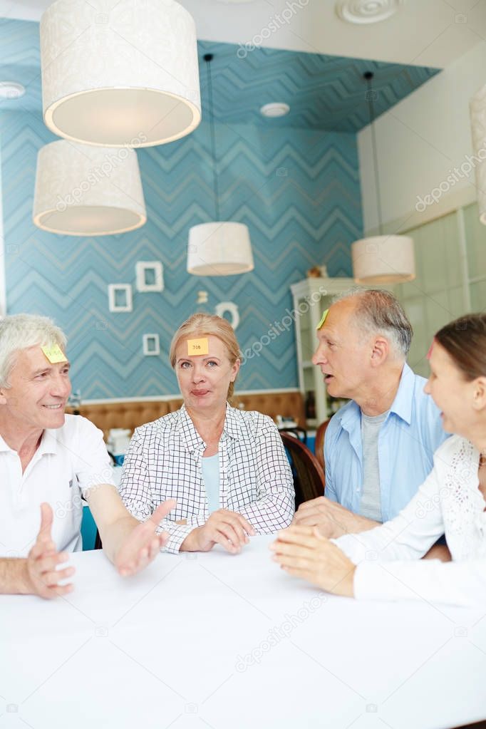 Group of senior friends with notepapers on foreheads playing name game at leisure