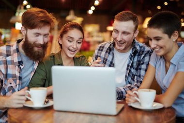 Güzel küçük kahvehane gayri resmi toplantıda: oturma tablo ve heyecanla dizüstü bilgisayar ekranına bakarak, bel, dikey gündelik giysiler içinde neşeli yöneticileri grubu