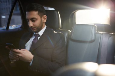 Arka koltukta pahalı araba içinde smartphone kullanarak yakışıklı Ortadoğu işadamı portresi