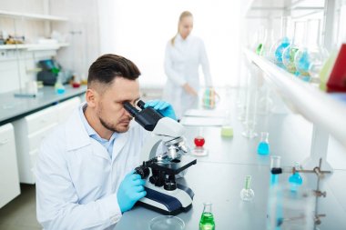 Modern laboratuvarda çalışan bilim adamları portresi: test tüpleri kontrollerimiz sıvı karıştırma kadınla masada mikroskop kullanarak adam