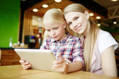 Genç bir kadın ve kızı onlne alışveriş veya ev için yemek siparişi verecek tablet ile