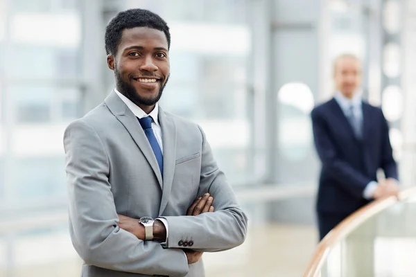 笑顔の肖像アフリカ系アメリカ人実業家の腕に自信を持ってカメラを見て渡ったバック グラウンドで 番目の男と近代的なオフィスビル — ストック写真