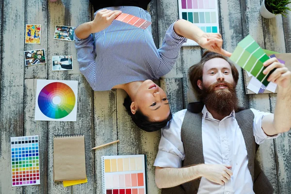 創造的なデザイナー チームのビューの上直接アジア女性とひげを生やした男は 木製の床の上に横たわるとプロジェクトを議論するモダンなスタジオで働いて配色パレットから — ストック写真