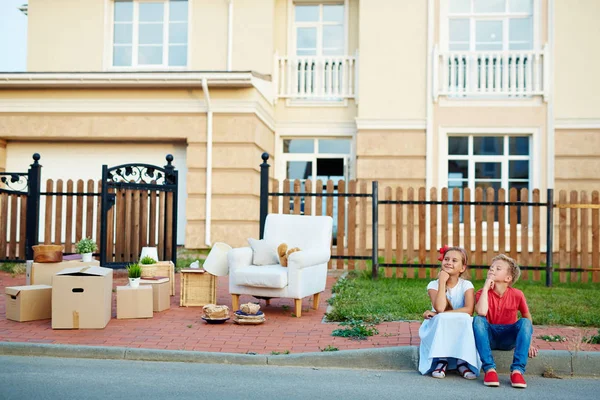 有趣的兄弟姐妹坐在路边 等待父母在搬迁期间 — 图库照片
