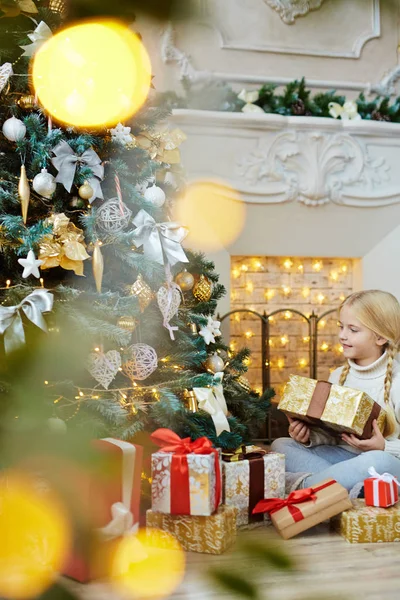小女孩与 Giftbox 坐在客厅的地板上的壁炉和看着美丽的圣诞树 — 图库照片